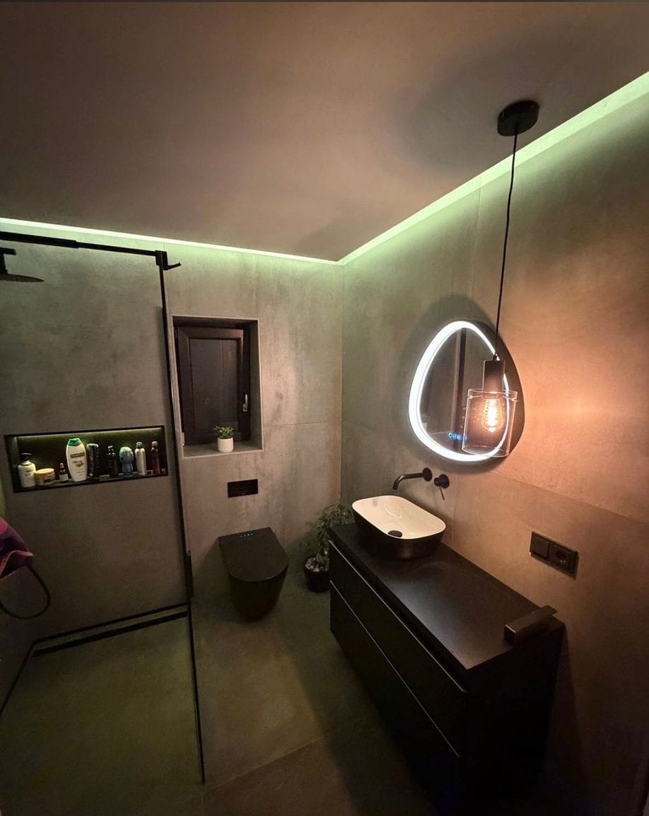 Fertiges Designbad in Betonoptik mit indirekter LED-Beleuchtung, beleuchtetem Spiegel und schwarzen Armaturen